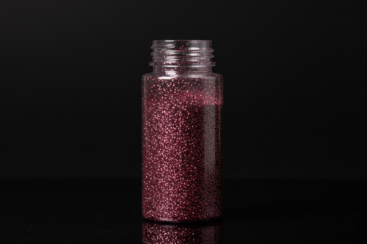 Plastic bottle of dark pink glitter on black background
