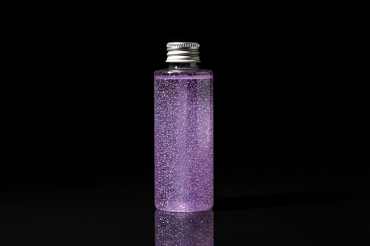 Plastic bottle of light purple glitter on black background